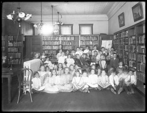Groepsportret van kinderen in de leeszaal van een niet-geïdentificeerde vestiging van de Queens Borough Public Library, c.1910