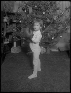 Ongeïdentificeerd kind dat voor een kerstboom staat met bokshandschoenen aan, 1915-16 door William Davis Hassler