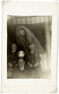 Paranormaal fenomeen: portret van drie oude mensen, de geest van een vrouw die achter hen verschijnt, circa 1920