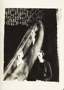 Paranormaal fenomeen: portret van een vrouw en twee mannen, en de geest van een vrouw die achter hen verschijnt, circa 1920