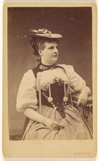 [Ongeïdentificeerde vrouw in klederdracht met hoed, zittend]. door A. Gabler