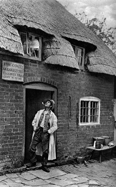 Een man die een pijp rookt buiten een winkel, Worcestershire, ca. 1922 door A. W. Cutler