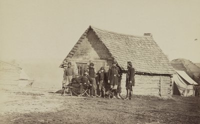 Een groep soldaten en twee jonge mannen, een Afro-Amerikaan, staan buiten blokhutkwartieren, 1861-65 door American Photographer