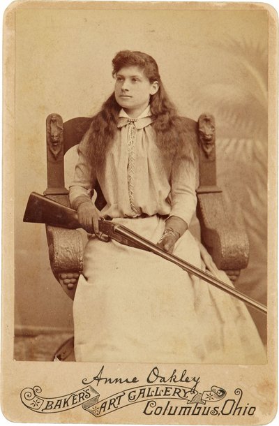 Annie Oakley: Hier zit de legendarische scherpschutter tamelijk bescheiden in een massieve Renaissance-stijl stoel, een geweer rustend op haar schoot. Haar delicate vrouwelijke trekken en vloeiende haar verbergen haar ruige buitenbeeld door American Photographer