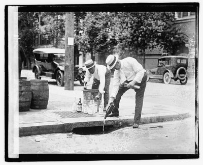 Twee mannen die drank in een riool gieten, 8 juli 1921 door American Photographer