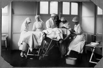 Eerste Wereldoorlog 1914-1918: artsen en verpleegsters van het Rode Kruis (Therese Pavillou?) behandelen een gewonde soldaat in het kamp van Couville in de Manche, Basse-Normandie, Frankrijk. Anonieme foto. door Anonymous Anonymous