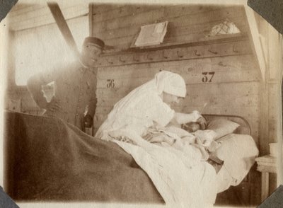 Eerste Wereldoorlog 1914-1918: verpleegster in een blouse scheert een soldaat (Franse oorlogswonden liggen in een bed), in Couville, Manche, Basse-Normandie, Frankrijk. Anonieme foto juli 1917. Privécollectie, Stella. door Anonymous Anonymous