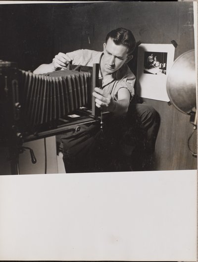 [Man past vouwbalg op grootformaat camera aan]. door Arnold Eagle
