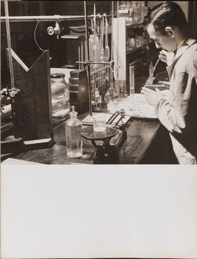 [Man in een lab gebruikt beide handen om een grote pipet in een bekerglas te plaatsen]. door Arnold Eagle