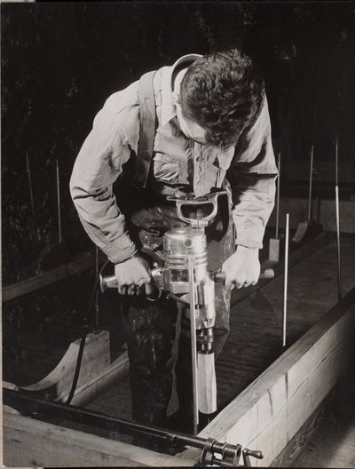 [Man gebruikt een handbediende machine om een stuk hout te bewerken]. door Arnold Eagle