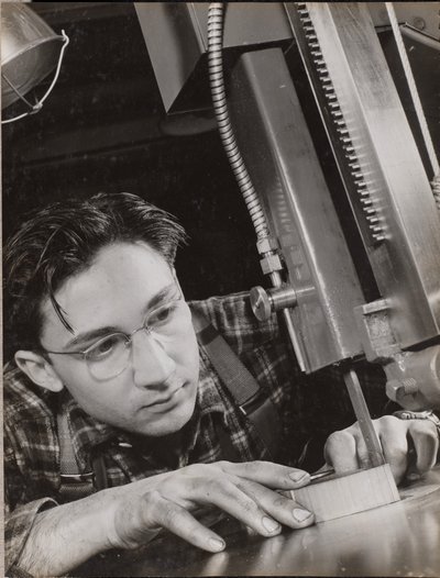 [Man met bril werkt geconcentreerd met een industriële vijl]. door Arnold Eagle
