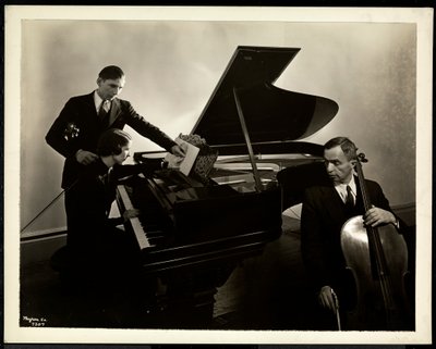 Blinde vrouw, Miss Harding, aan de piano die twee blinde mannen op de viool en cello instrueert, 1936 door Byron Company