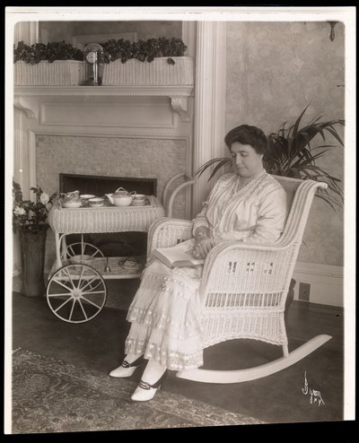 Mevrouw Howard zittend met een boek in een schommelstoel in haar huis op 200, 5th Avenue, New York, 1915-6 door Byron Company