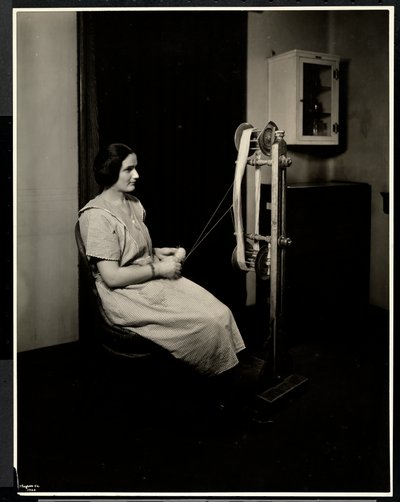 Portret van een blinde, dove en stomme jonge vrouw die wol spint bij de New York Association for the Blind, 111 East 59th St., New York door Byron Company