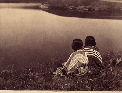 Een moment van rust: Piegan Indianen zittend aan de rand van een waterlichaam. Foto uit volume 6 van de encyclopedie gepubliceerd door Edward S. Curtis over de Indianen van Noord-Amerika, met een voorwoord van Theodore Roosevelt. door Edward Sheriff Curtis