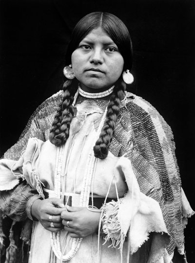 Cayuse vrouw, halflang portret, staand, naar voren gericht, vlechten, schelpschijf oorbellen, schelpkralen choker en schelpkralen om de nek, geborduurde hertenleren jurk met geborduurde riem c. 1910, foto Edward S. Curtis door Edward Sheriff Curtis