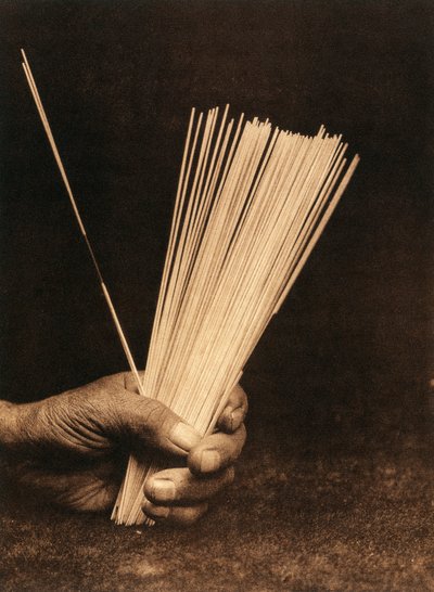 Close-up van de hand van een Indiaan van de Hupa-stam of dorp die waarzeggerijstaven vasthoudt door Edward Sheriff Curtis