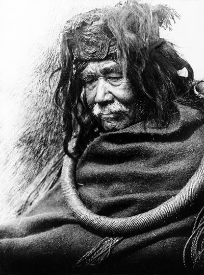 De Hamatsa, Nakoaktok c. 1910 Halflang portret van Nakoaktok man, naar links kijkend, met cederwortel ceremoniële lus. door Edward Sheriff Curtis