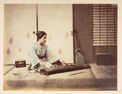 Zingende meisjes [Japan], Studiportret van een jonge Japanse vrouw zittend op een tatami-mat die een snaarinstrument bespeelt, Fotograaf: Onbekend Lucas Collectie: Fotografisch verslag van de wereldreis van Charles James en Morton P, Lucas door English Photographer