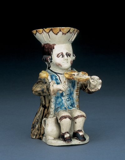 Fiddler toby jug, zijn hoed met bruine en gele geschulpte rand, zijn bruine haar ingekerfd en vastgebonden met een witte rozet, in een gewassen bruine rokjas, c.1770 door English School
