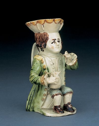 Toper toby jug, zijn hoed met bruine en gele geschulpte rand, zijn ingekerfde bruine haar vastgebonden met een witte rozet, zittend met een balusterkan op zijn knie, c.1770 door English School