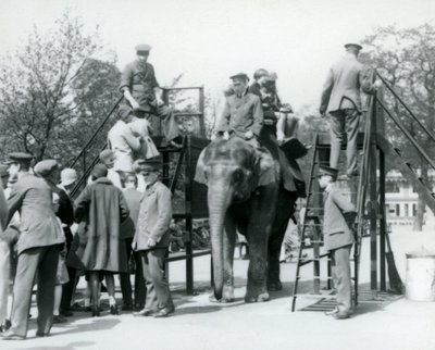 Bezoekers in de rij voor een Olifantenrit terwijl anderen instappen met de hulp van vijf verzorgers, London Zoo, 1927 door Frederick William Bond
