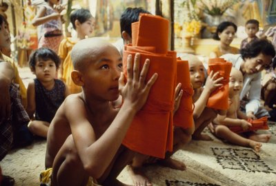 Een jonge jongen met geschoren hoofd ontvangt zijn monnikskleding. Mandalay, Birma door James L Stanfield