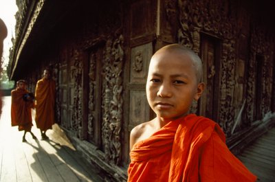 Een jonge novice monnik voor gebeeldhouwde teakpanelen. Shwenandaw-klooster, Mandalay, Birma door James L Stanfield