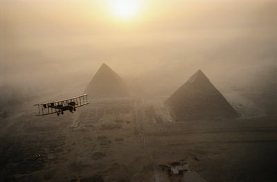 Het vintage vliegtuig Vimy vliegt boven mistige piramides tijdens een gouden zonsopgang door James L Stanfield