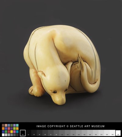 Netsuke gemodelleerd als een liggende hond door Japanese School