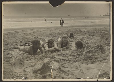 [Kinderen liggen in het zand op het strand]. door Louis Fleckenstein
