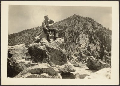 [Man zittend op rotsen]. door Louis Fleckenstein