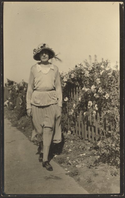 [Vrouw loopt langs hek met bloemen]. door Louis Fleckenstein