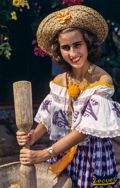 Vrouw in strohoed van Panama maalt met een traditionele vijzel en stamper. door Luis Marden
