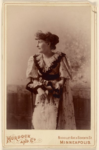 [Ongeïdentificeerde vrouw in profiel, leunend op een stoel, met een veren waaier]. door Murdock and Company