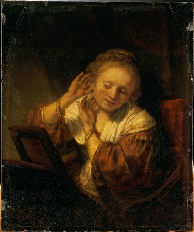 Jonge vrouw die zich met oorbellen siert door Rembrandt van Rijn