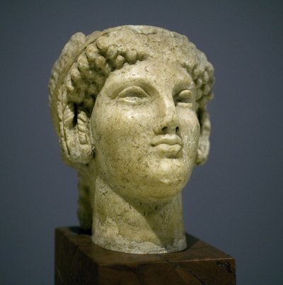 Meisjeshoofd (Kore), sculptuur uit de Romeins-Hellenistische periode (3e-2e eeuw na onze jaartelling), zeer expressief gezicht, prominente jukbeenderen naar het oosten, glimlach, krullend haar, archaïsche stijl van Ionië in de 6e eeuw voor onze jaartelling door Roman