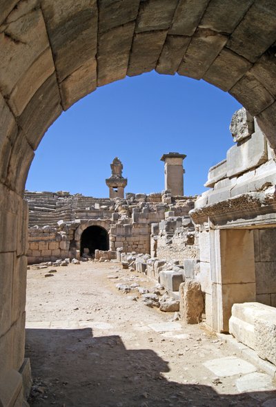 Uitzicht door de gewelfde ingang van het Xanthos-theater naar de orkestbak, met zuil en Harpy-tombe, Xanthos, Turkije (foto) door Roman