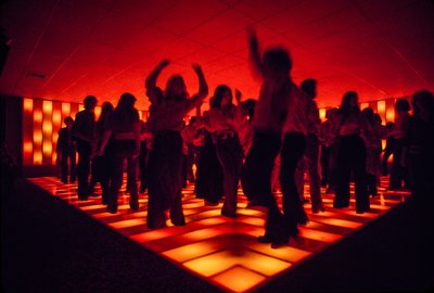 Jonge dansers in een discotheek dansen op een verlichte vloer door Ted Spiegel