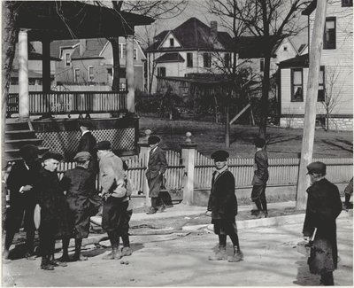 Een groep jongens in winterjassen die op een onbekende straat staan, voor of na een schooldag. door Unbekannt
