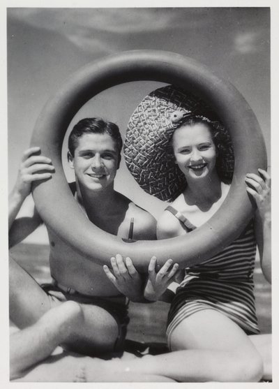 Man en vrouw die door een rubberen ring op het strand kijken, circa 1935 door Unbekannt