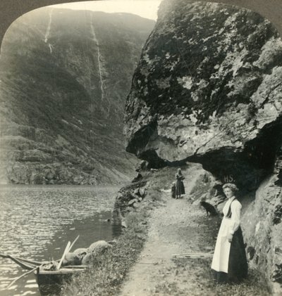 Waar de weg onder de uitstekende kliffen door kruipt bij de wateren van de Nerofjord, Noorwegen, ca. 1905 door Unbekannt
