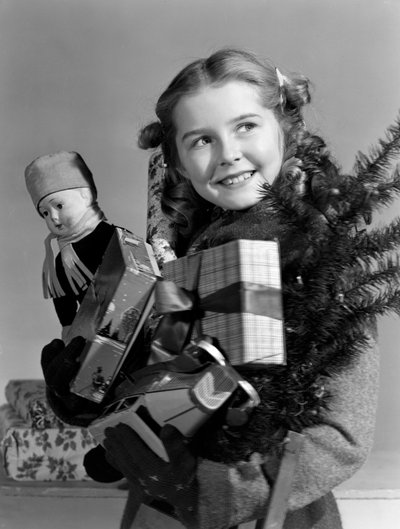 Jong meisje met een armvol kerstcadeaus, ca. 1950 door Unbekannt