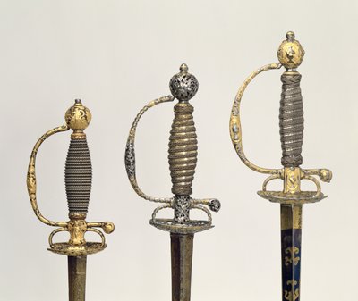 Heften van drie Franse zwaarden: een van staal, geblauwd en versierd met ontwerpen in gegraveerd goud, c.1730; een van staal, doorboord en gegraveerd en de grond van gematteerd goud, c.1760; een van gegraveerd staal door Unbekannt Unbekannt