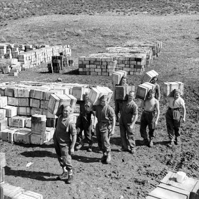 Een compo rantsoendepot en mannen die meer voorraden dragen, maart 1943 door Unbekannt