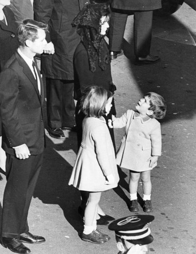 Kleine John Kennedy kijkt op naar zijn moeder, alsof hij wil zeggen: 