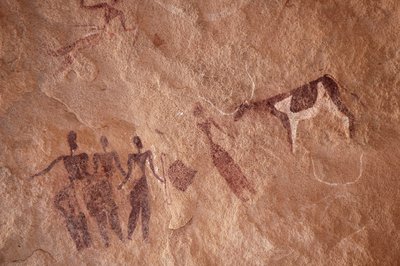 Rotstekeningen, Prehistorie: Rotsschildering van een groep personages en een tweekleurige koe met grote hoorns in een versierd onderkomen, in het Uweinat-massief, Egypte. (Periode van 8000 tot 3000 jaar v.Chr.). Fotografie door Unbekannt
