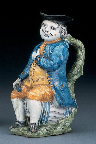Toby-kruik met bleek mangaan gezicht en handen, houdend een lege bolvormige buffkleurige kruik in gewassen blauwe jas en broek, en groene vest, ca. 1800 door Unbekannt