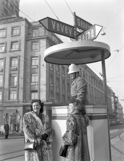 Twee Amerikaanse jonge vrouwen praten met een politieagent in Lausanne, 4 januari 1949: Met de politieagent door Unbekannt