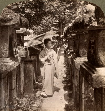 Een vrouw Shinto-aanhanger telt de stenen lantaarns, Kasuga-schrijn, Nara, Japan door Underwood and Underwood
